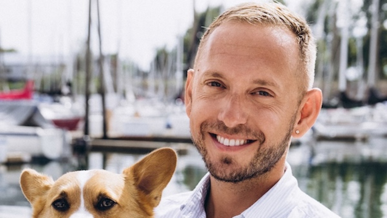 Skylar Windham, founder of HitchPiggy, with a dog at a marina.